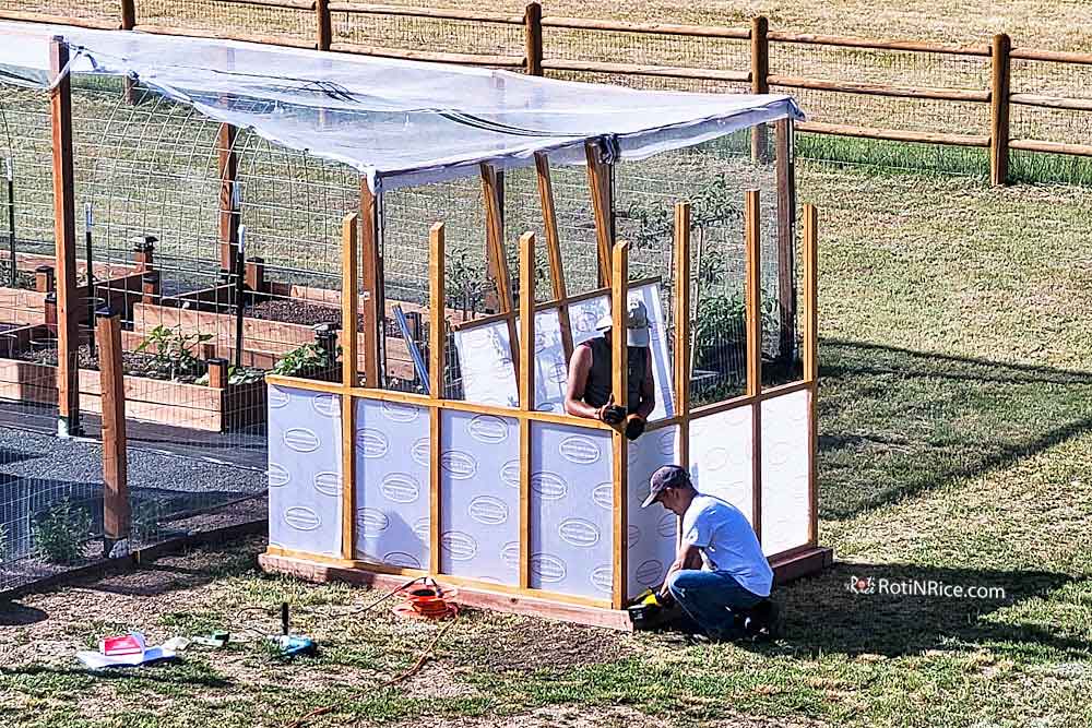 Attaching the partially assembled walls of the greenhouse onto the 4"x4" base.