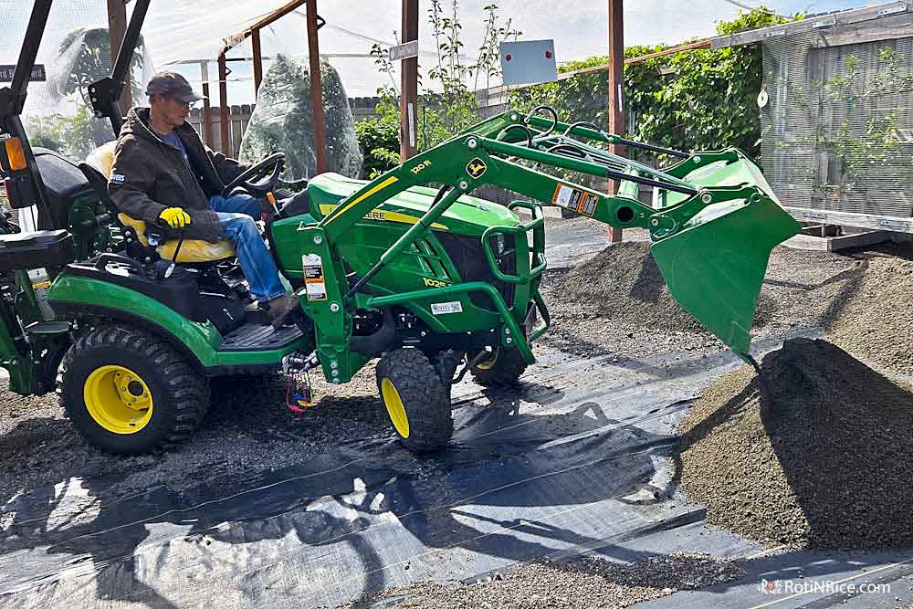 Using the front loader tractor to move the crushed rocks to the orchard.